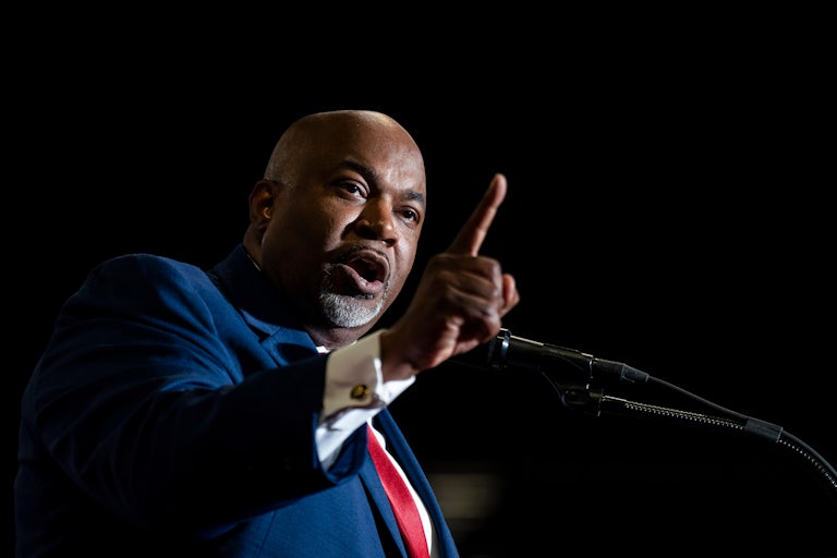 Mark Robinson speaks at a mic and points his finger as if in warning