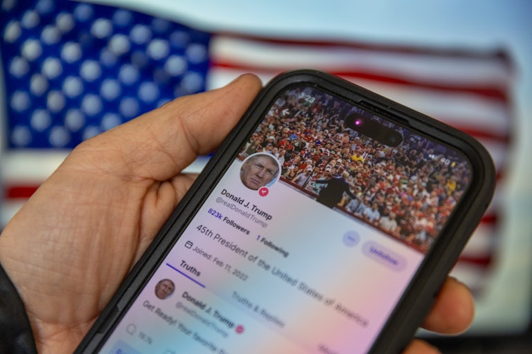 A phone screen shows Donald Trump’s Truth Social account