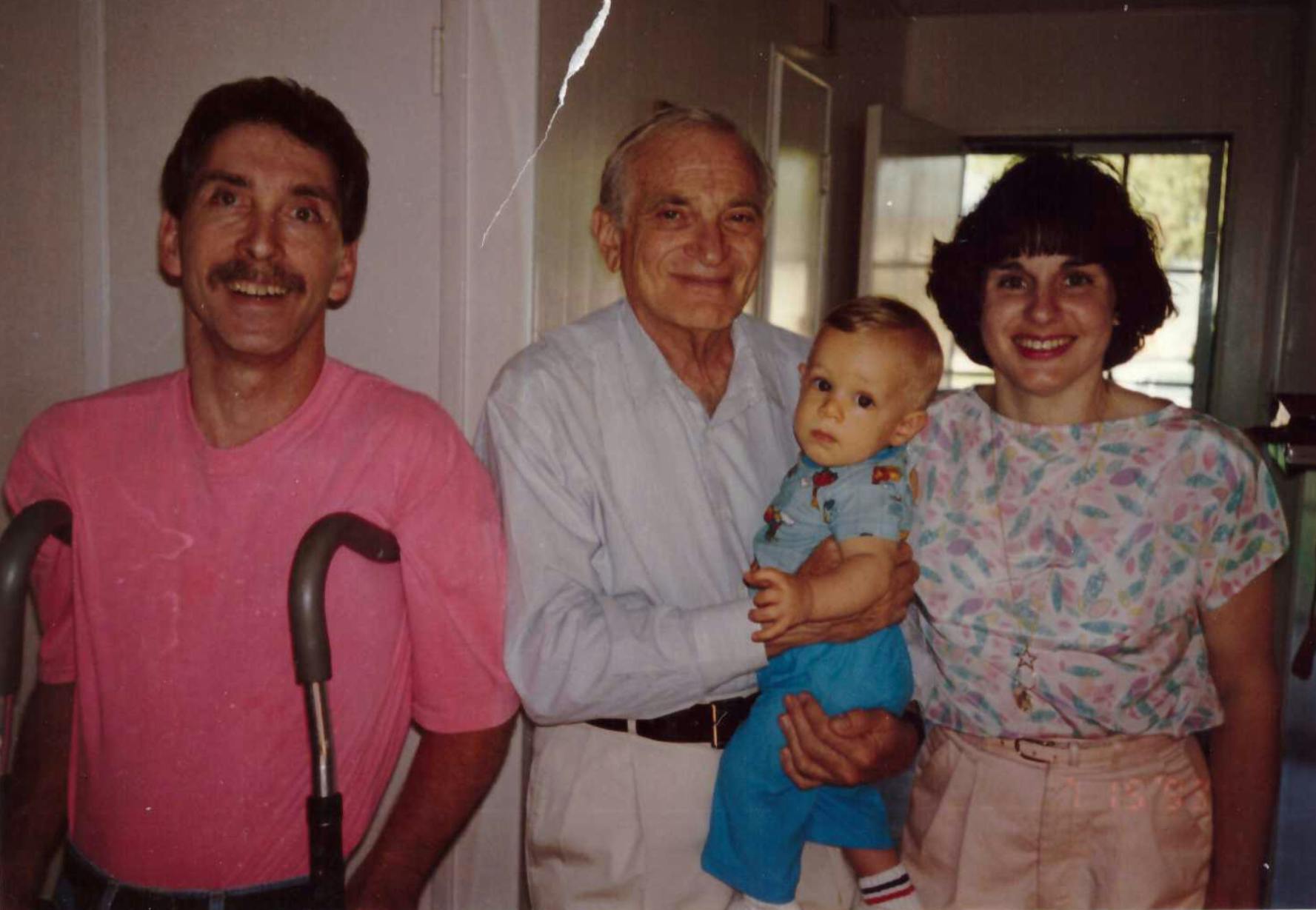 the author as a baby held by a doctor, with his parents standing on either side