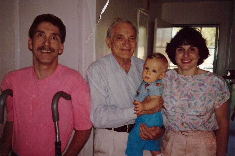 the author as a baby held by a doctor, with his parents standing on either side