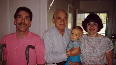 the author as a baby held by a doctor, with his parents standing on either side
