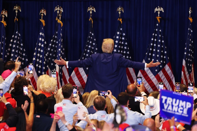 Donald Trump turns away from an audience at a rally while holding his arms out