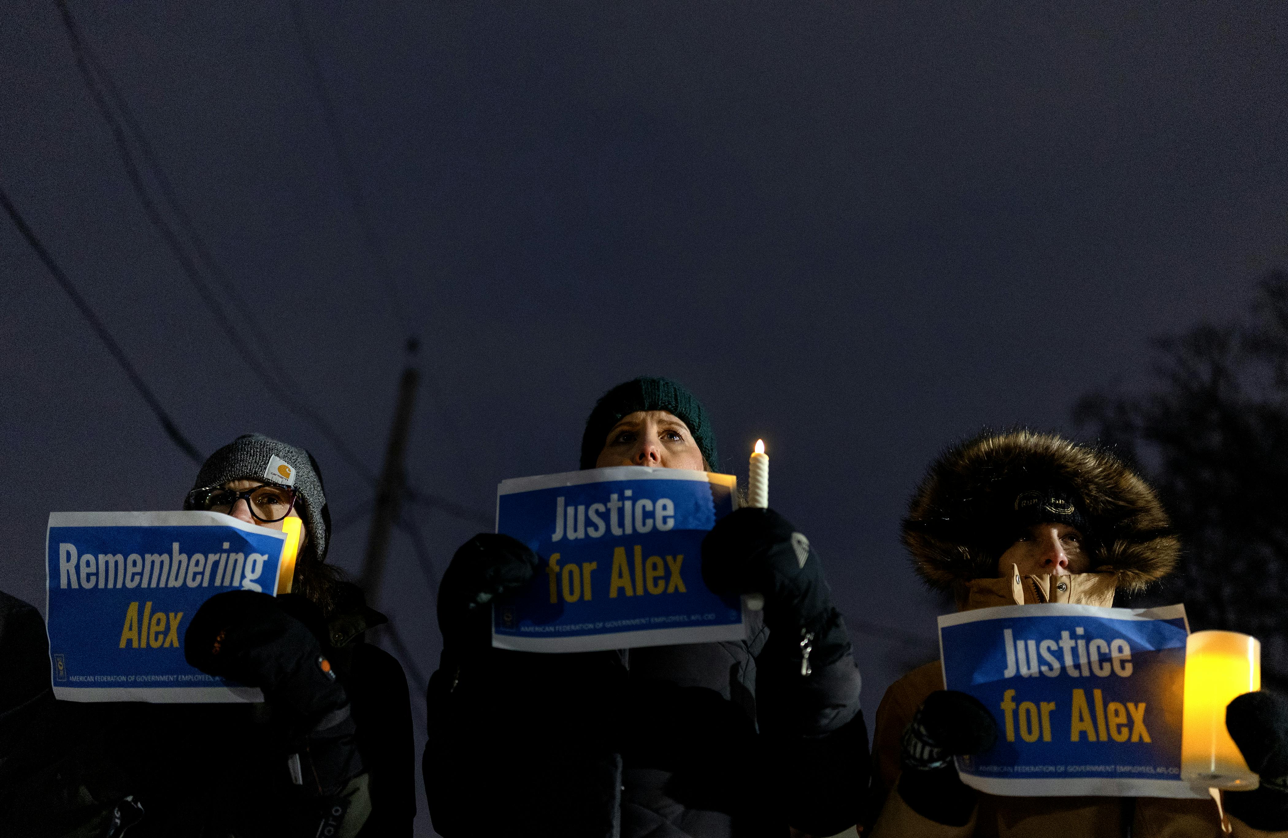 Three people hold up signs in memory of Alex Pretti during a vigil for him in Minneapolis, Minnesota