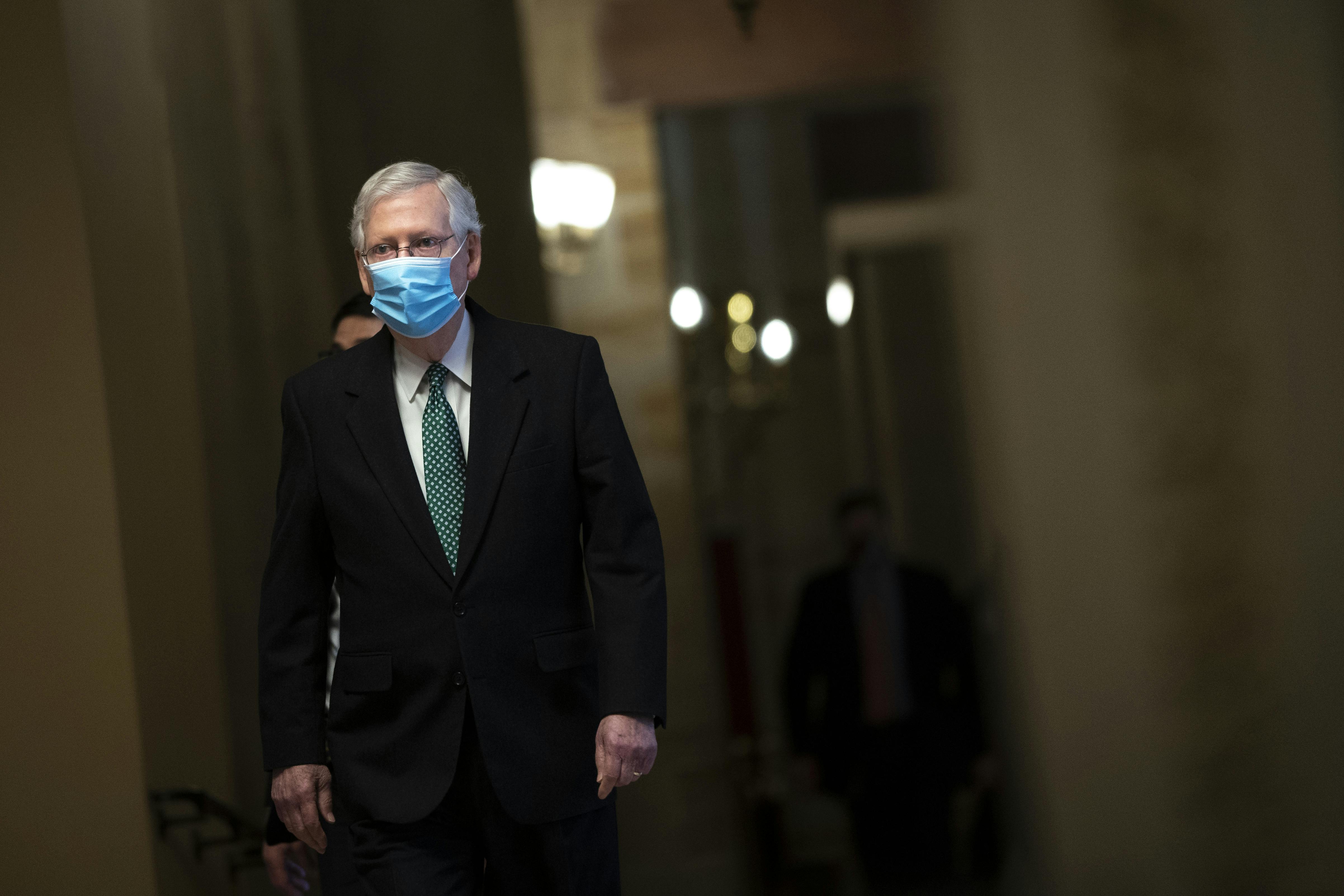 Minority Leader Mitch McConnell walks to the Senate Chamber wearing a mask. 