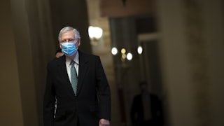Minority Leader Mitch McConnell walks to the Senate Chamber wearing a mask. 
