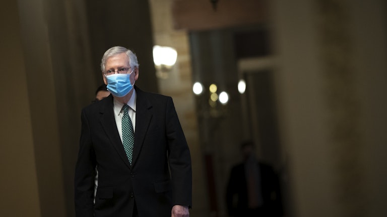 Minority Leader Mitch McConnell walks to the Senate Chamber wearing a mask. 