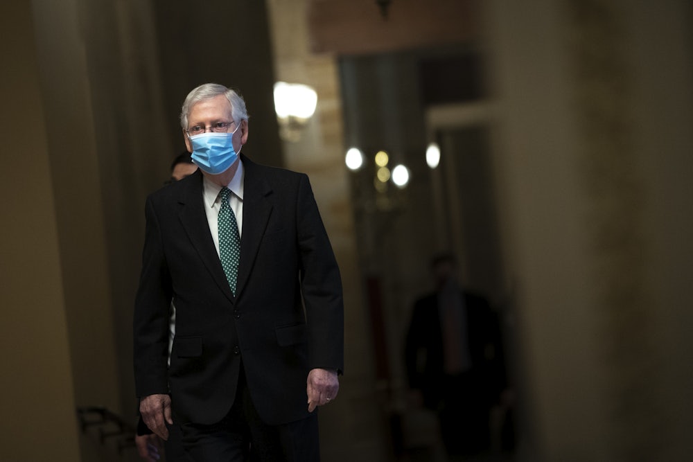 Minority Leader Mitch McConnell walks to the Senate Chamber wearing a mask.