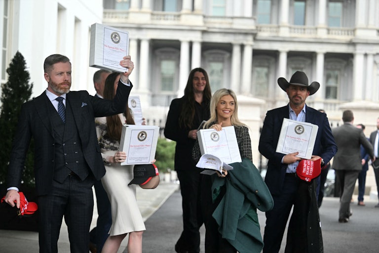 Multiple people smile and show off binders reading "The Epstein Files: Phase 1" as they walk out of the White House.
