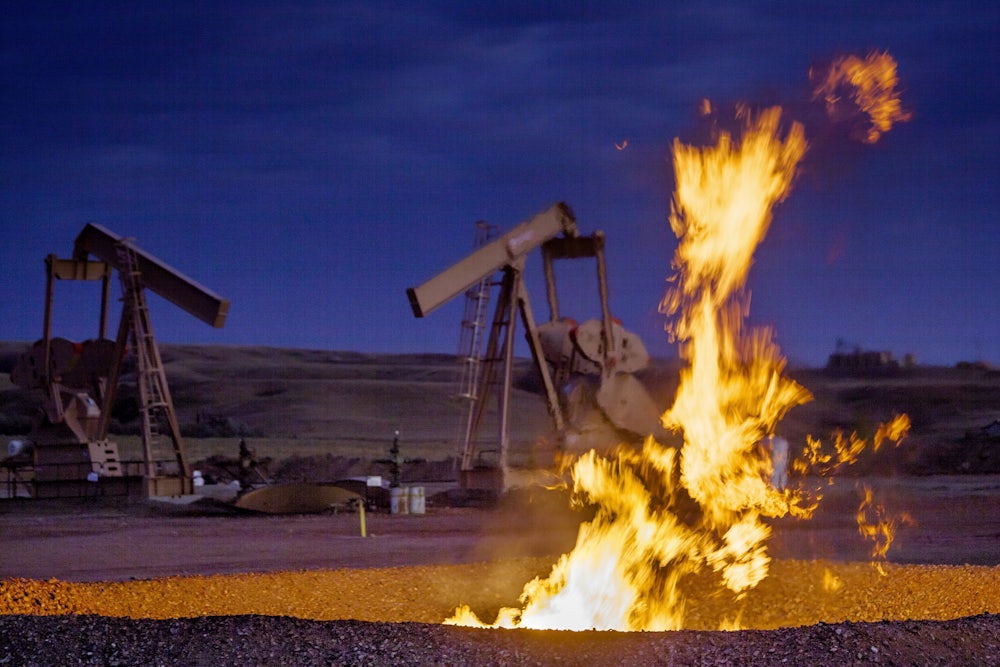 Flames rise out of a pit with two pumpjacks in the background.