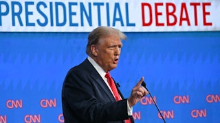 Donald Trump gestures while speaking into a microphone