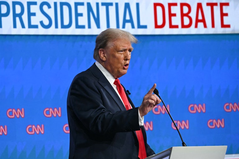 Donald Trump gestures while speaking into a microphone