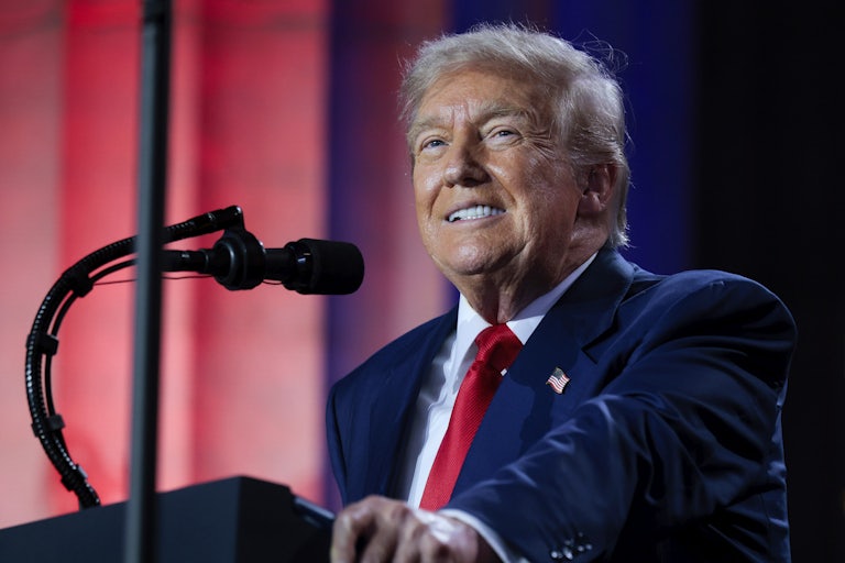Donald Trump smiles while standing at a podium