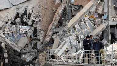 People stand amid rubble in Tehran