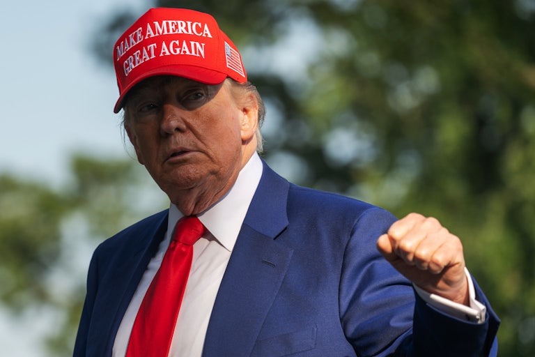 Donald Trump raises his fist while walking outside the White House
