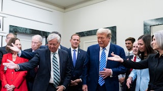 Donald Trump is in the center of the photo, as Republican senators including Lindsey Graham surround him and all extend a hand as if to let Trump walk first.