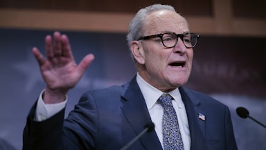 Senator Chuck Schumer gestures with one hand while speaking at a podium