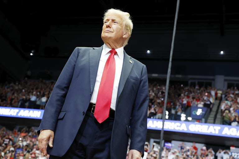 Donald Trump stands and smiles at a rally