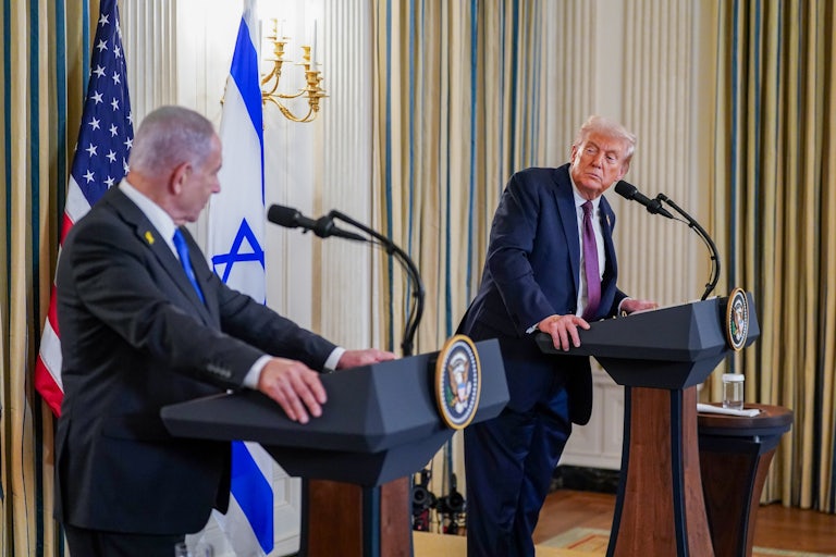 Trump looks over at Netanyahu as both speak at podiums in the White House.