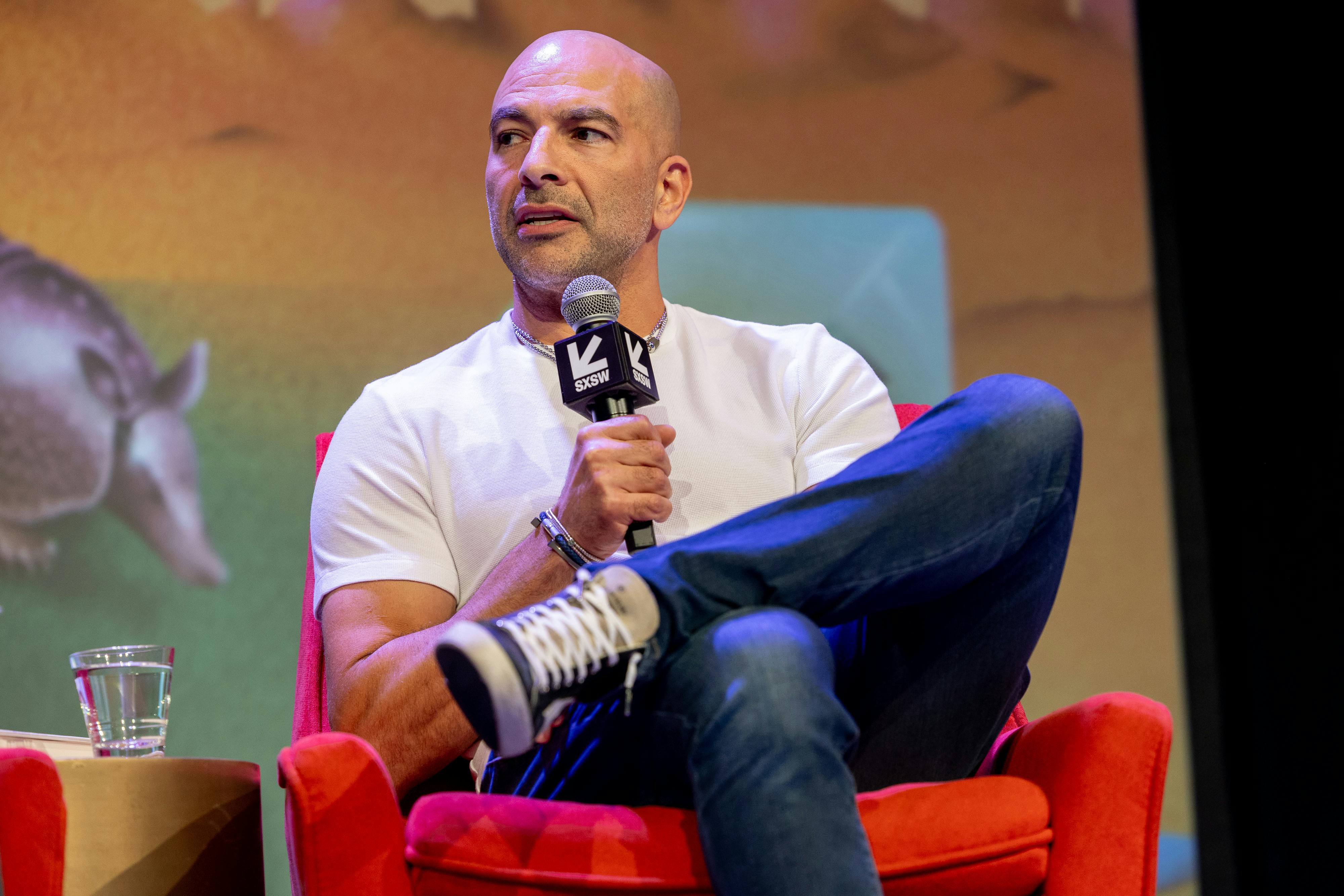 Peter Attia speaks with legs crossed at a conference