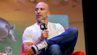 Peter Attia speaks with legs crossed at a conference