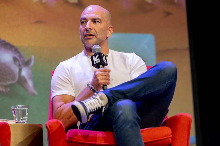 Peter Attia speaks with legs crossed at a conference