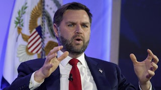 Vice President JD Vance gestures and speaks while sitting on stage during an event
