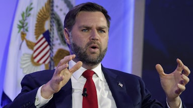 Vice President JD Vance gestures and speaks while sitting on stage during an event