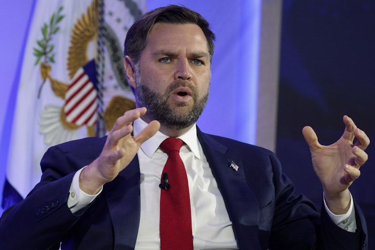 Vice President JD Vance gestures and speaks while sitting on stage during an event