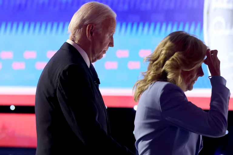 President Joe Biden walks off with first lady Jill Biden, who puts her hand on her head.