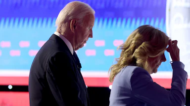 President Joe Biden walks off with first lady Jill Biden, who puts her hand on her head.