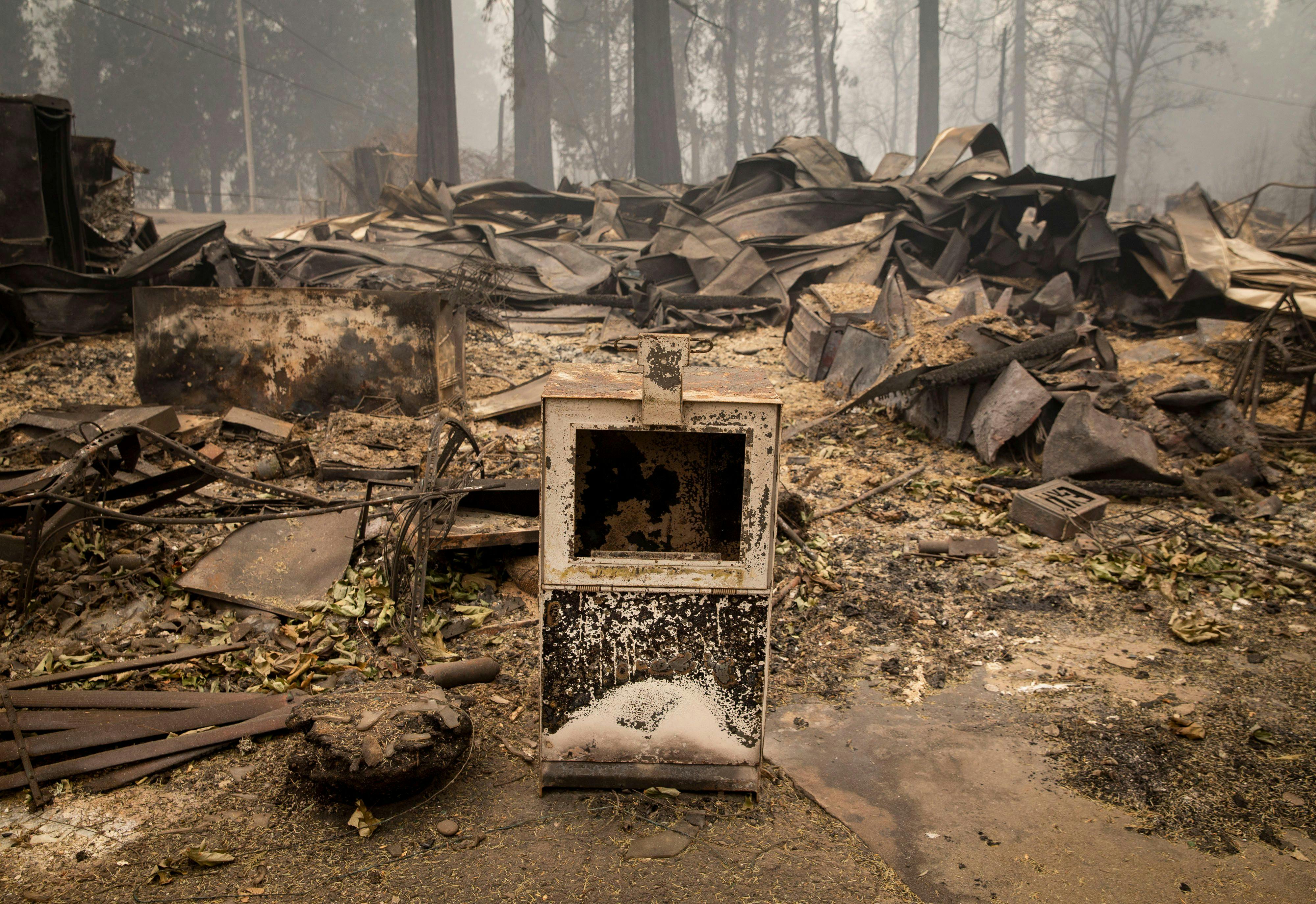 A newspaper box sits along the road near a burned out business in Blue River, Oregon.