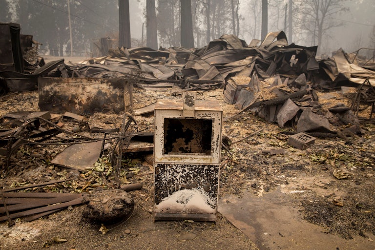 A newspaper box sits along the road near a burned out business in Blue River, Oregon.