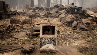 A newspaper box sits along the road near a burned out business in Blue River, Oregon.
