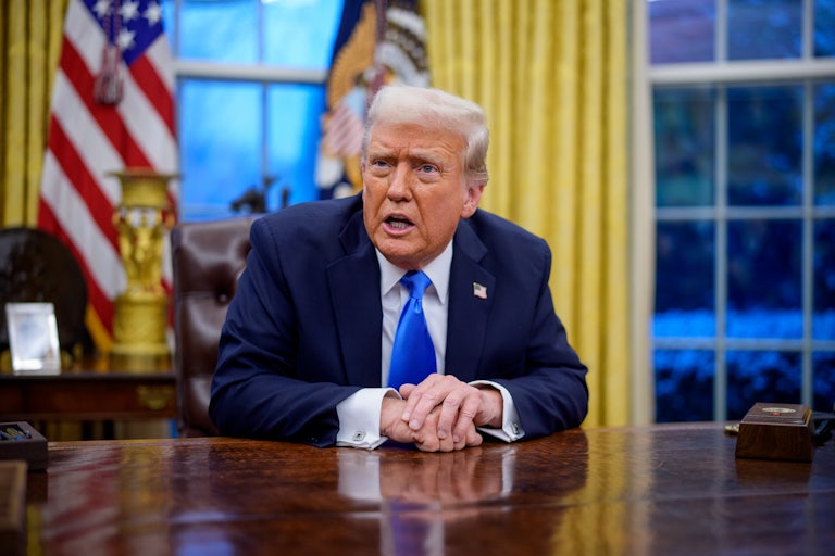 Donald Trump speaks with his hands on his desk in the Oval Office.