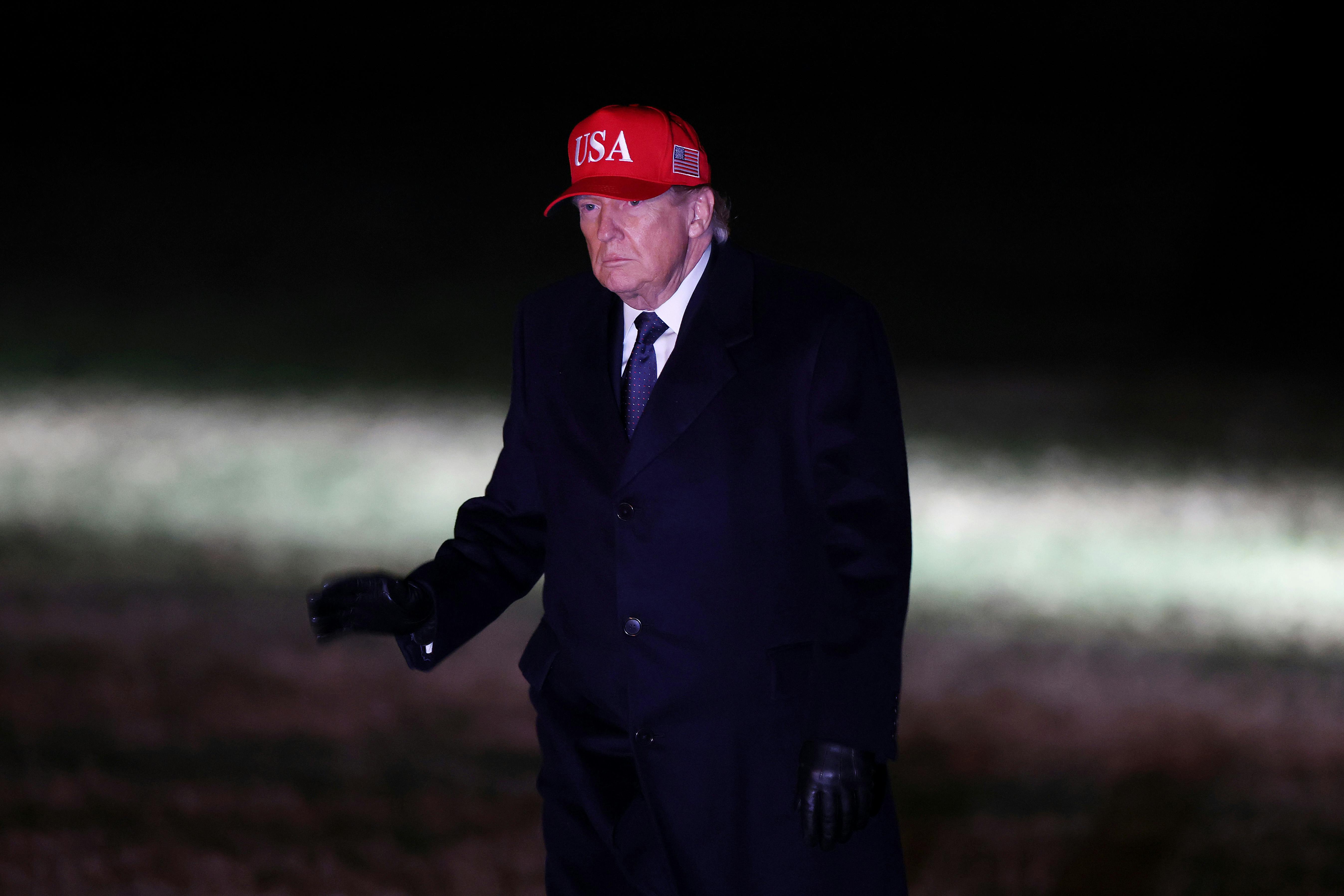 Donald Trump walks across the South Lawn as he returns to the White House.