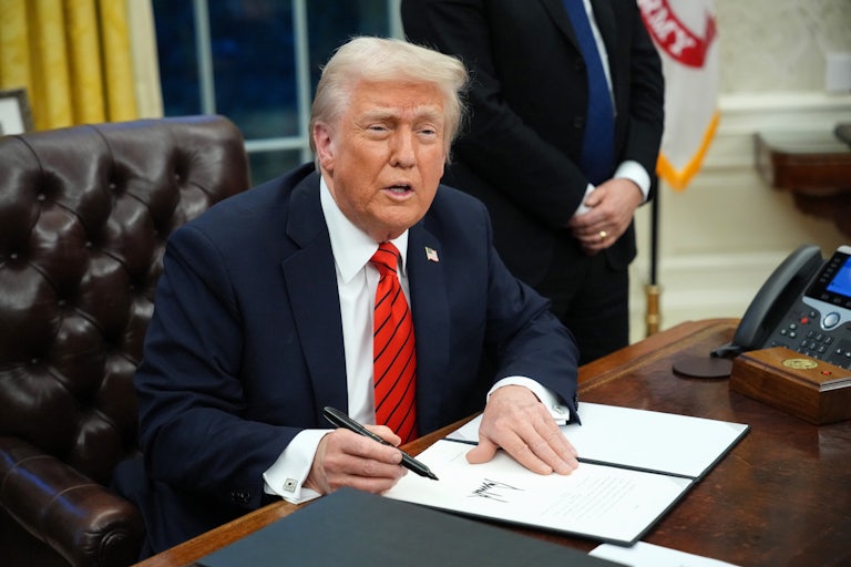 Donald Trump speaks while signing an executive order at his desk in the Oval Office.