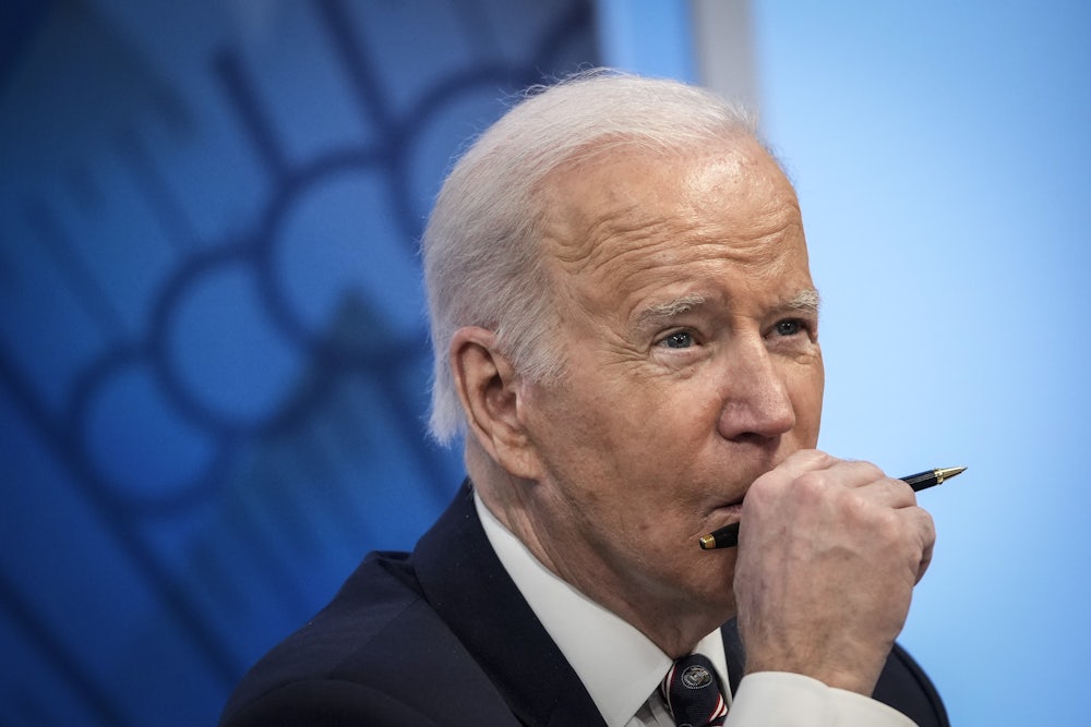 A close up of a pensive President Joe Biden, holding a pen in front of his face.