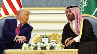 Donald Trump and Saudi Crown Prince Mohammed bin Salman lean over to speak to each other while seated with a table between them.