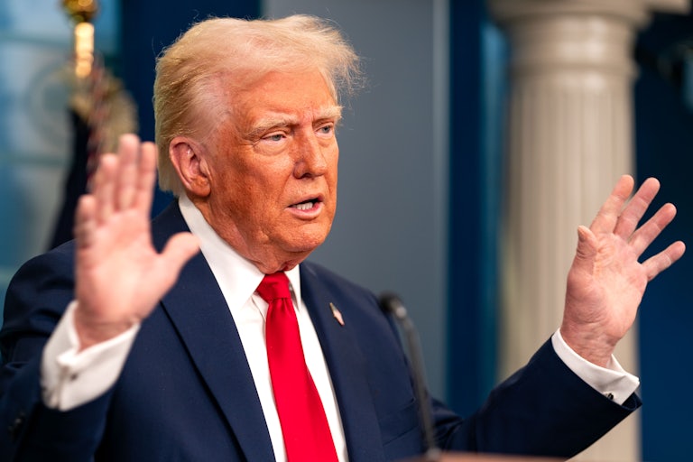 Donald Trump holds his hands up while speaking to reporters