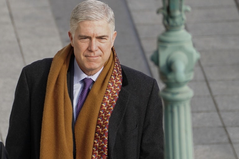 A close up of Justice Neil Gorsuch as he walks outside.