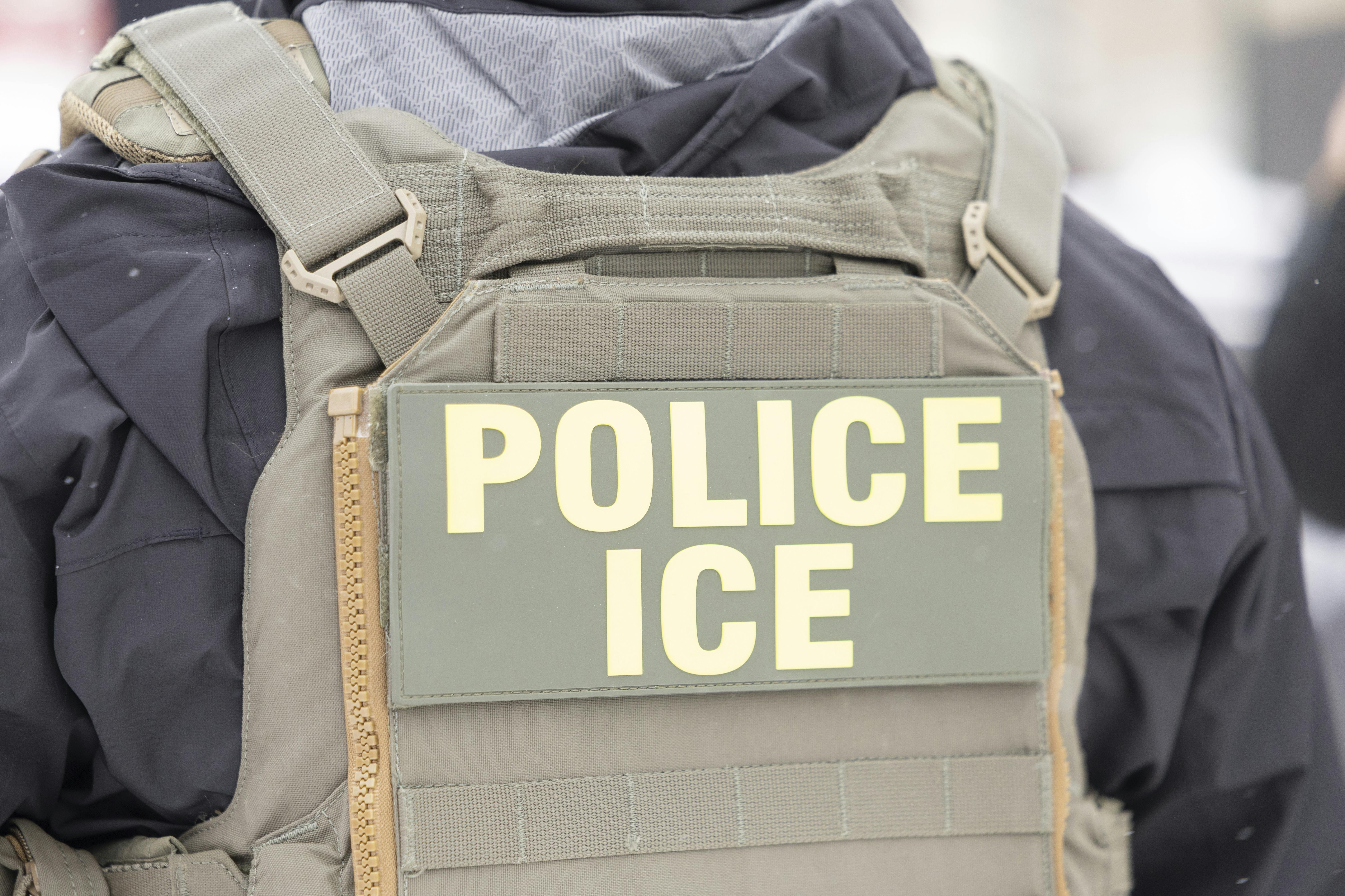 An immigration officer wears a vest that says, "Police ICE"