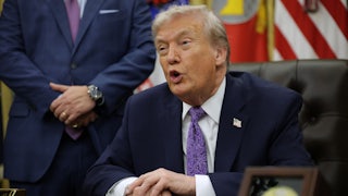 Donald Trump speaks while seated at his desk in the Oval Office of the White House. He places his left hand on his right one, which has the bruise.