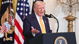 Donald Trump gestures with one hand speaks at a podium