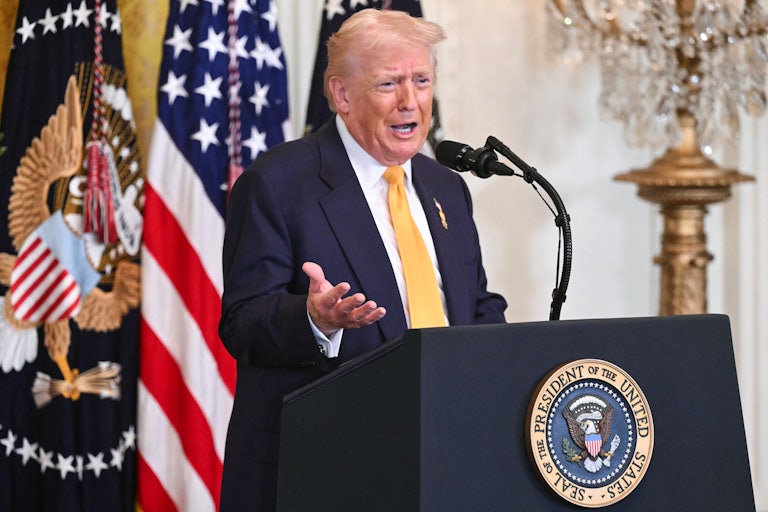 Donald Trump gestures with one hand speaks at a podium
