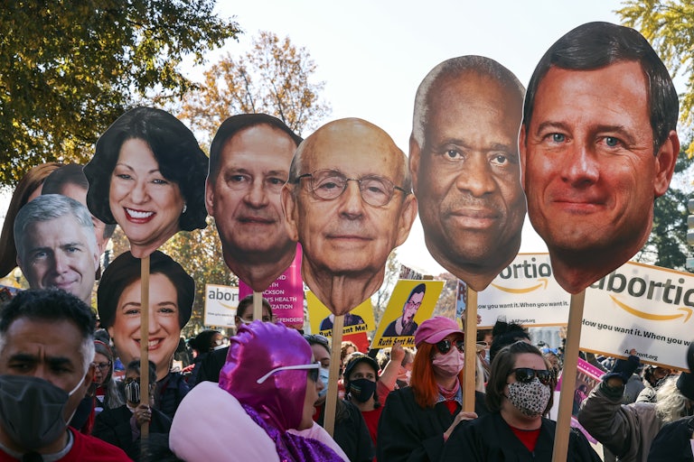Protesters hold up giant depictions of the Supreme Court Justices’ heads outside the Supreme Court building.