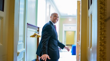 A smiling Senator Cory Booker looks back to wave goodbye as he leaves a room.