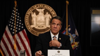 New York Governor Andrew Cuomo speaks at a news conference with flags and a state seal behind him. 