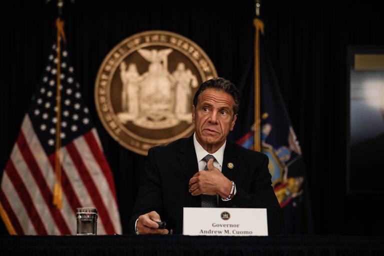 New York Governor Andrew Cuomo speaks at a news conference with flags and a state seal behind him. 