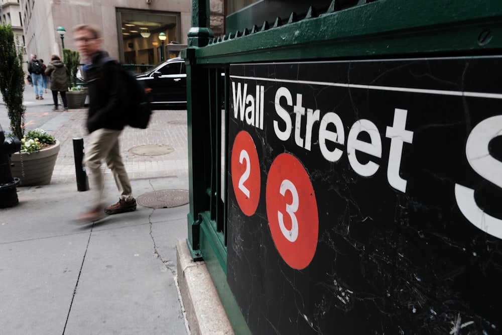 An image of the Wall Street subway entrance in New York, with a blurry figure walking past it.