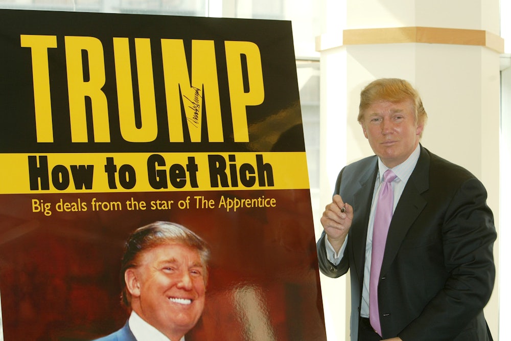 Donald Trump stands in front of a poster advertising one of his books.